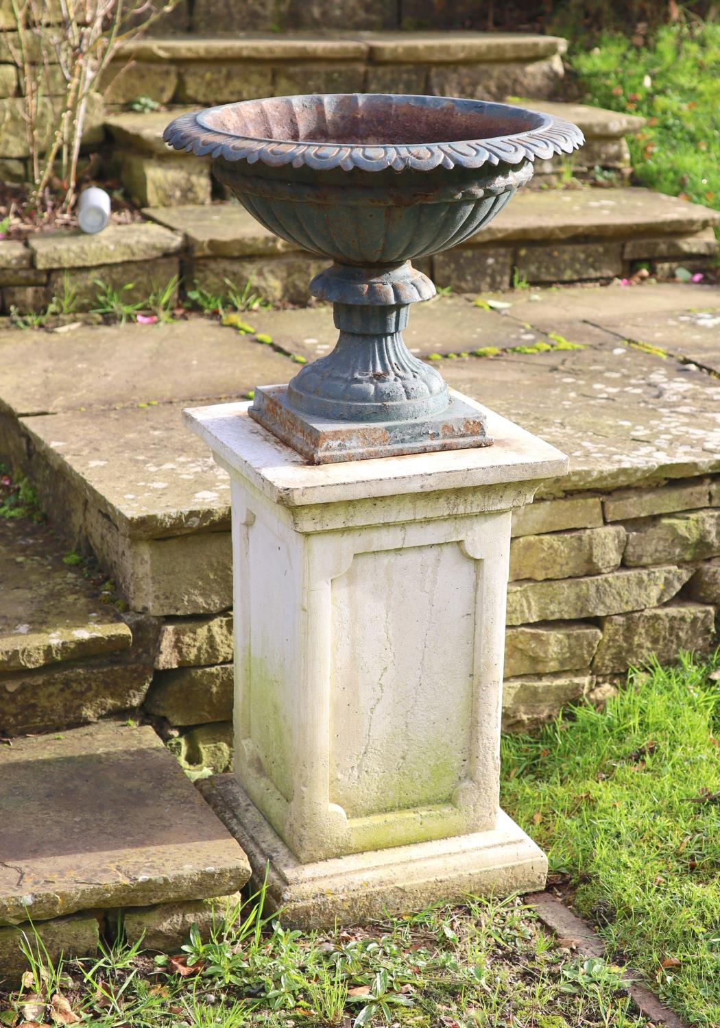 A pair of green painted cast iron garden urns on reconstituted stone pedestals, diameter 52cm height