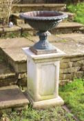 A pair of green painted cast iron garden urns on reconstituted stone pedestals, diameter 52cm height