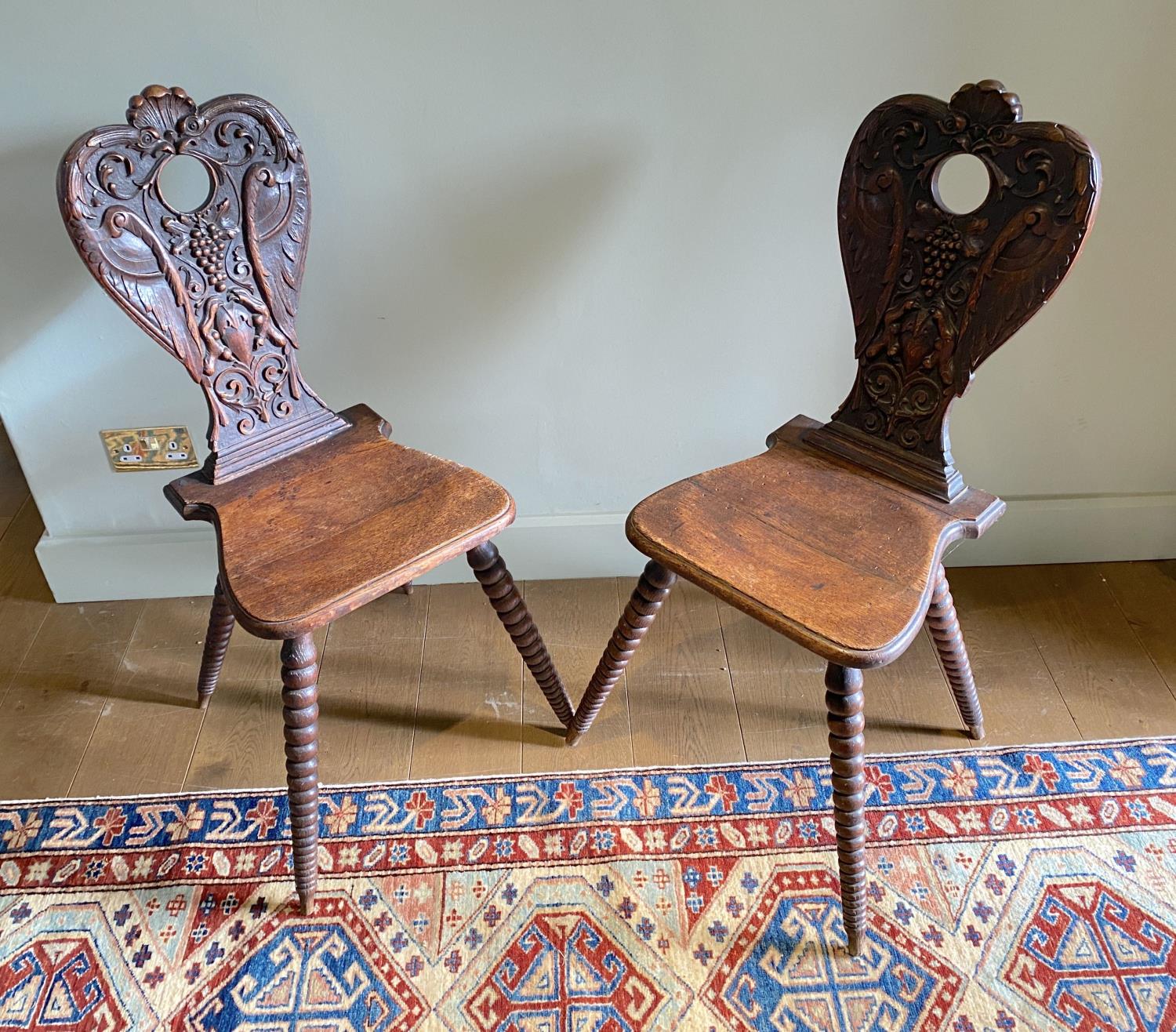 A pair of 19th century Swiss carved oak hall chairs, with vine and scroll backs and tapered bobbin