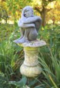 A simulated lead resin garden statue of a seated man, height 49cm, with a damaged marble pedestal,