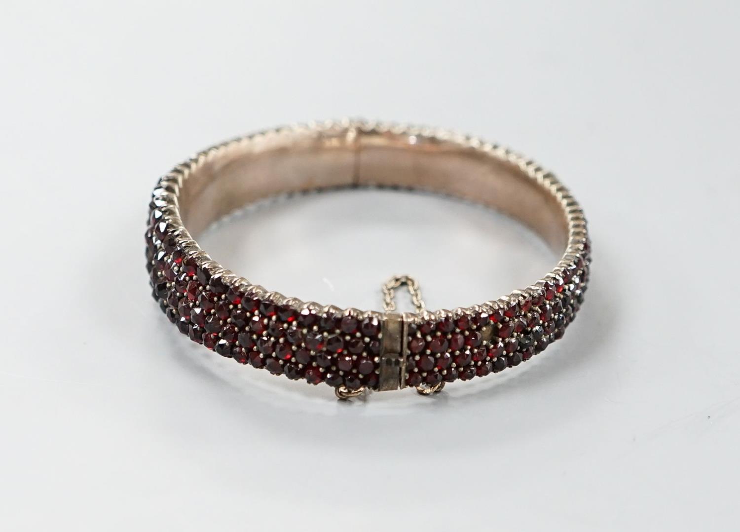 A late Victorian gilt white metal and garnet encrusted hinged bangle (stone missing). - Image 2 of 4