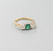 A modern 18ct gold, emerald and diamond set three stone ring, size O, gross weight 3.1 grams.