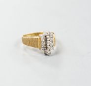 A 1970's textured 18ct gold and thirteen stone diamond set geometric dress ring, size Q, gross