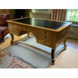 A Biedermeier style maple desk, with black leather skiver and seven drawers, on ebonised scroll legs