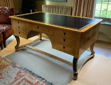 A Biedermeier style maple desk, with black leather skiver and seven drawers, on ebonised scroll legs