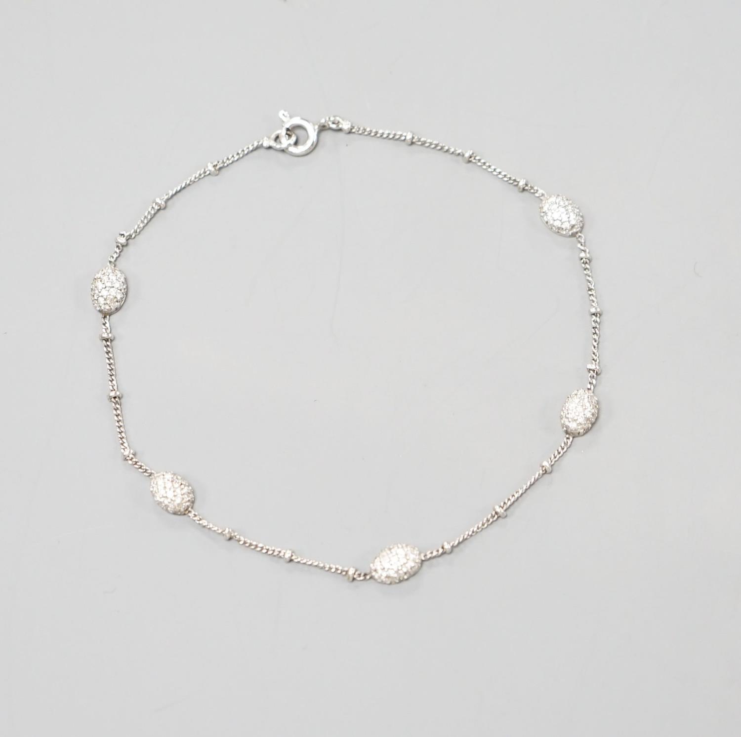 A modern 750 white metal and diamond chip set demi lune link bracelet, 19cm,gross weight 3.1 grams.