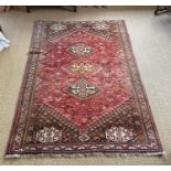 A Persian red ground rug, with three central hectagons and floral borders, 236 x 161cm