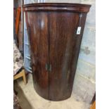 A George III oak bow-fronted hanging corner cabinet, width 73cm, depth 52cm, height 132cm