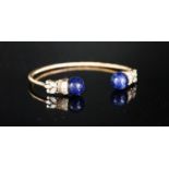 A modern yellow metal twist, two stone sodalite? and diamond set open bangle, gross weight 14