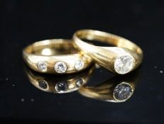 A modern 18ct gold and gypsy set solitaire diamond ring, size X and a similar three stone diamond