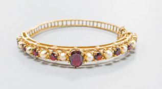A 9ct gold, garnet and cultured pearl set hinged bracelet, gross weight 16.1 grams.