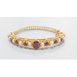 A 9ct gold, garnet and cultured pearl set hinged bracelet, gross weight 16.1 grams.