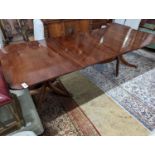 A reproduction George III style mahogany twin pillar extending dining table, two spare leaves,