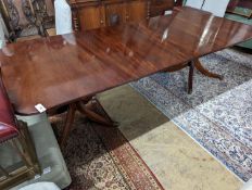 A reproduction George III style mahogany twin pillar extending dining table, two spare leaves,