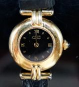 A lady's gilt white metal Must De Cartier quart wrist watch, on a Cartier leather strap.
