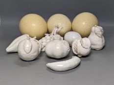 A decorative collection of tin glazed model fruits, together with three ostrich eggs