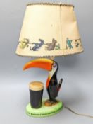 A Guinness toucan lamp, with original shade, tail repairedTotal height including shade 43.5 cm