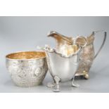 A Victorian repousse silver sugar bowl, a George III silver cream jug and a later silver cream jug,
