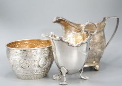 A Victorian repousse silver sugar bowl, a George III silver cream jug and a later silver cream jug,