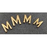 Four yellow metal letter 'M' appliques, gross weight 2.4 grams.