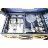 A George V traveling toilet case, fitted with fourteen silver mounted backed brushes, a mirror and