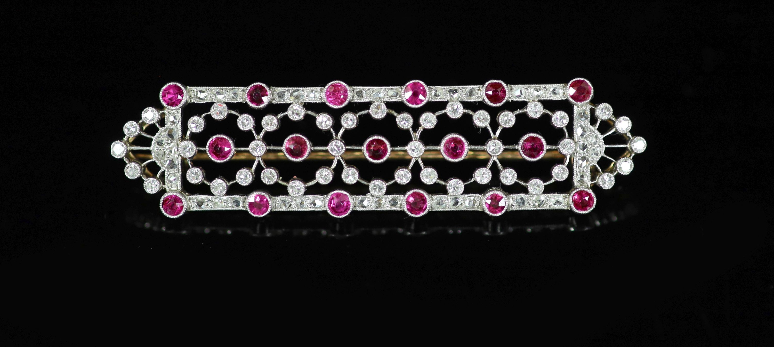 A 1920's/1930's style pierced gold and platinum, ruby and diamond chip millegrain set shaped