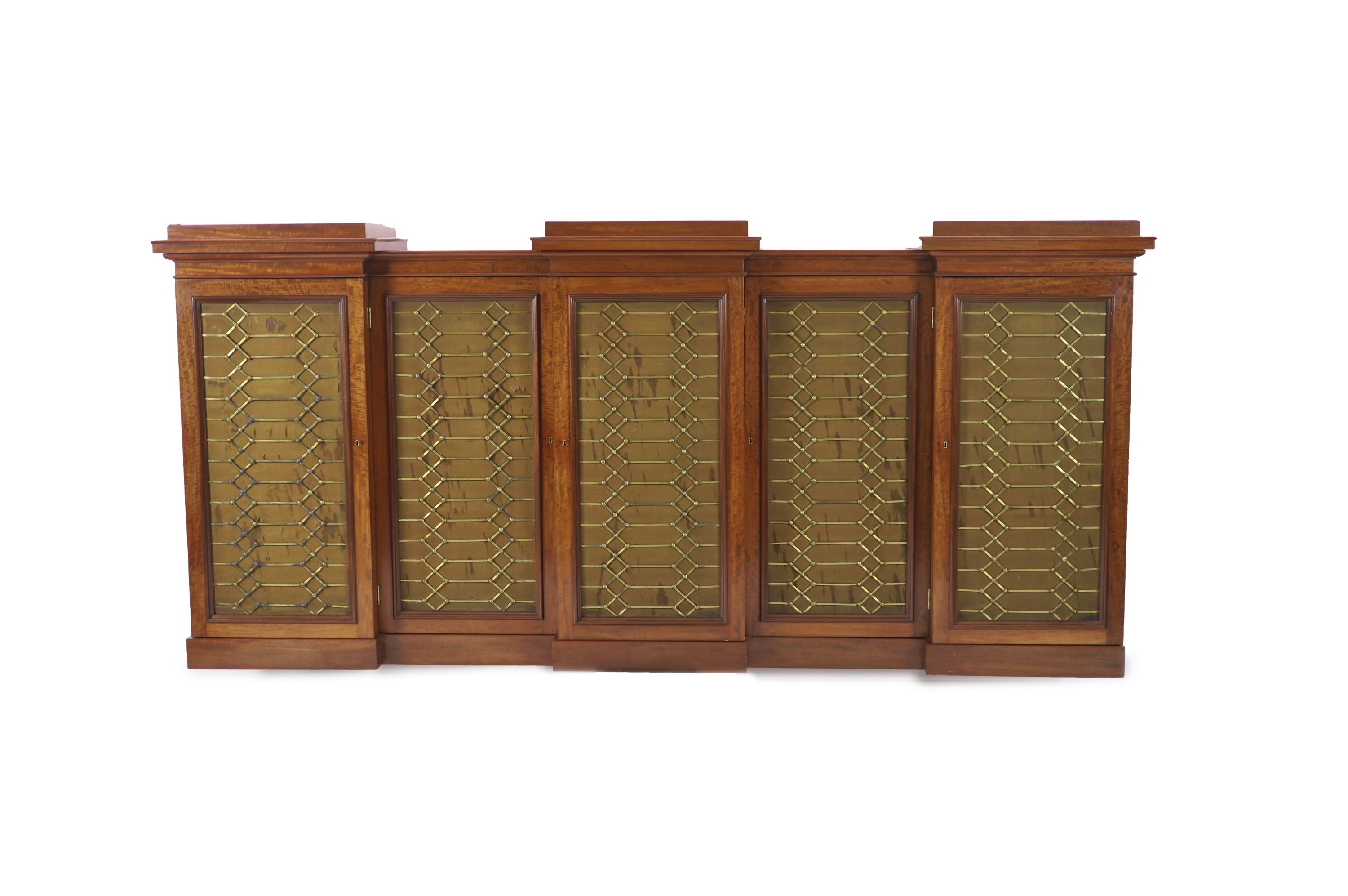 An early Victorian flame mahogany triple breakfront library cabinet,fitted five brass grilled
