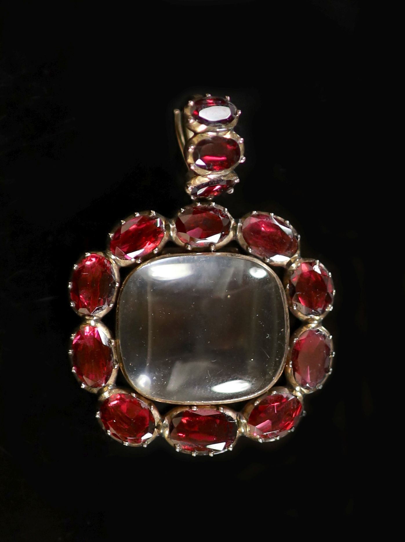 A Victorian gold, rock crystal and thirteen stone foil backed oval cut garnet set pendant,with