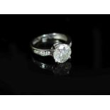 A modern white gold and single stone diamond ring, with eight stone diamond set shoulders,the