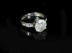A modern white gold and single stone diamond ring, with eight stone diamond set shoulders,the