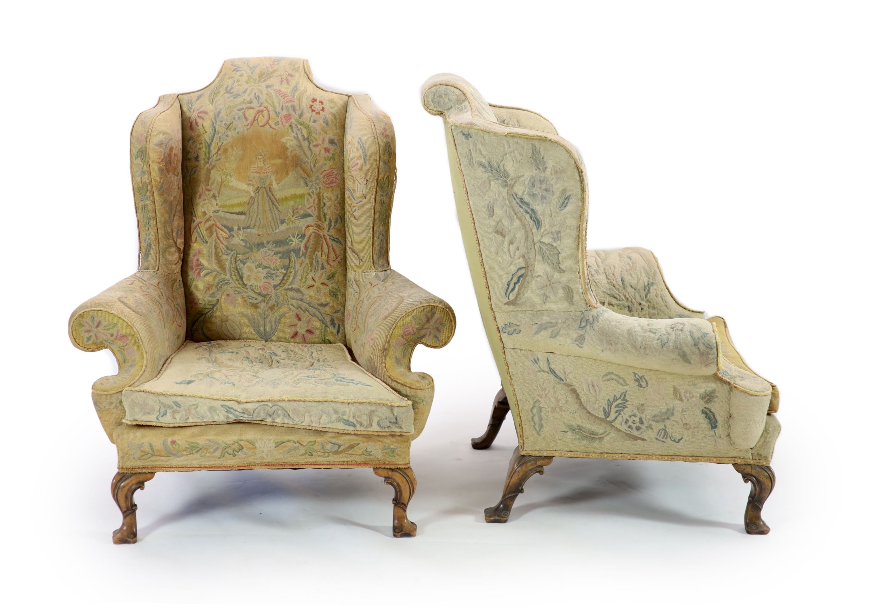 A pair of Georgian style mahogany wing armchairsof generous proportions, upholstered in faded