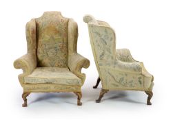 A pair of Georgian style mahogany wing armchairsof generous proportions, upholstered in faded