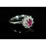 A white gold, ruby and diamond set flower head cluster ring,with central oval cut ruby, size R,