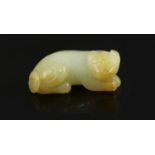 A Chinese pale celadon and russet jade figure of a lion dog,recumbent pose looking to its right,6.