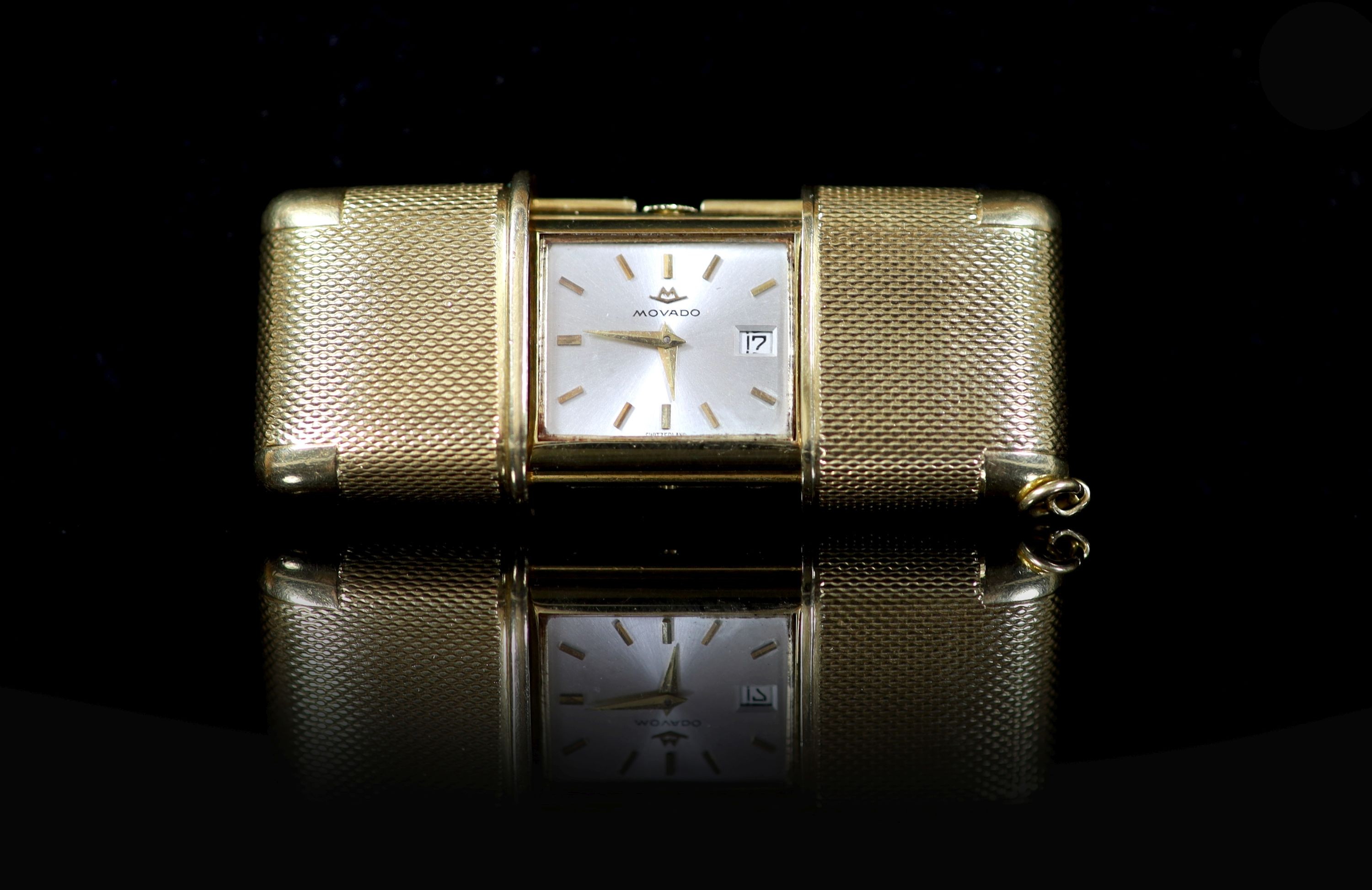 An engine turned 18ct gold cased Movado travelling watch,with baton numerals and date aperture, case