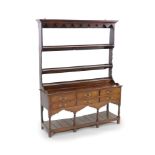 A George III oak dresser,with two shelf rack and six long drawers over a pot board, on stile feet,