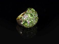 A Continental 18k gold and graduated round cut peridot encrusted dress ring, with diamond chip