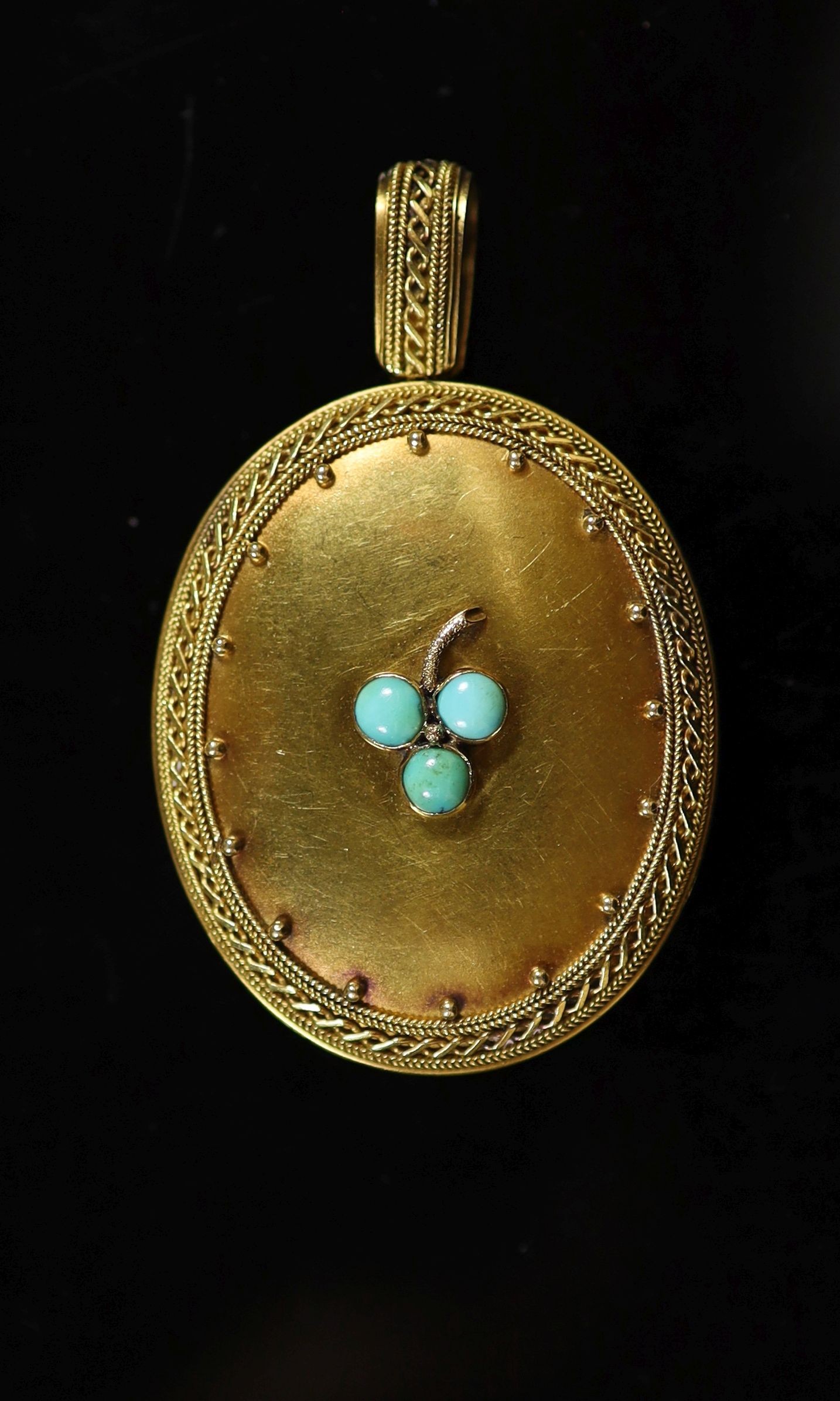 A Victorian gold and three stone turquoise set oval locket,with cannetille style border decoration