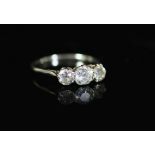 A white gold and three stone diamond set ring,the central old round cut stone weighing approximately