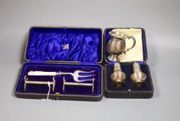 A 1920's silver small mug, a cased pair of silver pepperettes and a cased pair of knife rests and