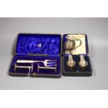 A 1920's silver small mug, a cased pair of silver pepperettes and a cased pair of knife rests and