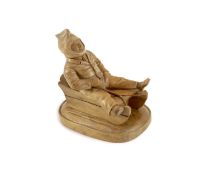 A North European novelty carved beech inkwell in the form of a seated figure sledging, c.1900,