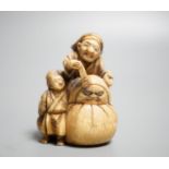 A Japanese ivory netsuke of an artisan and apprentice painting a Daruma doll, early 20th century,