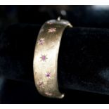 A 1960's engraved 9ct gold and ruby set hinged bracelet, interior diameter 58mm, gross weight 35.7