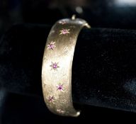 A 1960's engraved 9ct gold and ruby set hinged bracelet, interior diameter 58mm, gross weight 35.7
