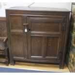 An early joined oak food cupboard, the planked top above a single hinged pierced panelled door,