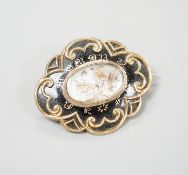 A Victorian yellow metal and black enamel cartouche shaped mourning brooch, with engraved