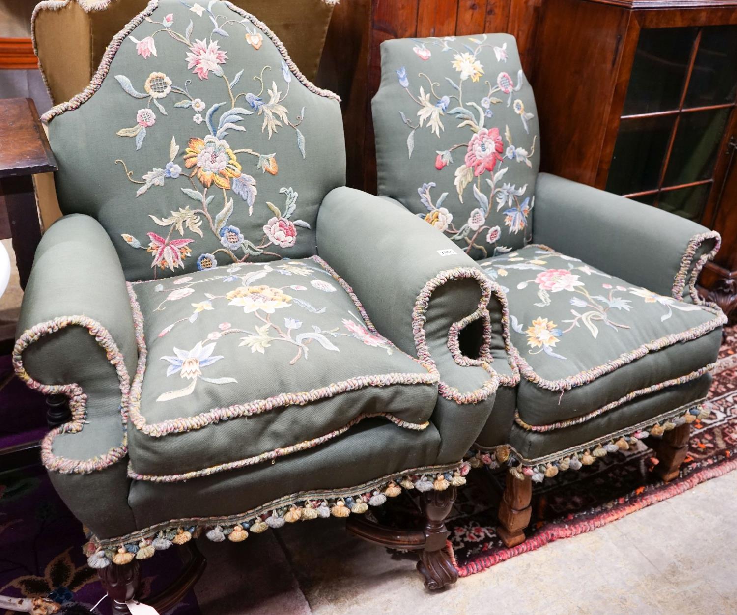 Two armchairs with shaped backs, each upholstered in green with embroidered flowers, on shaped cross
