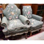 Two armchairs with shaped backs, each upholstered in green with embroidered flowers, on shaped cross