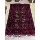 A Belouch red ground rug woven with octagonal motifs, 190 x 124 cms.